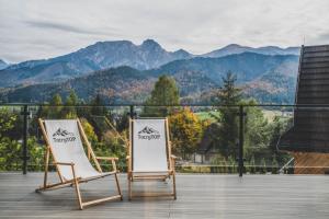 two chairs on a deck with mountains in the background at Czarne Wierchy Domy Premium in Kościelisko