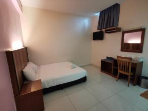 Kleines Zimmer mit einem Bett, einem Schreibtisch und einem Tisch in der Unterkunft Sweet Star Hotel in Alor Setar