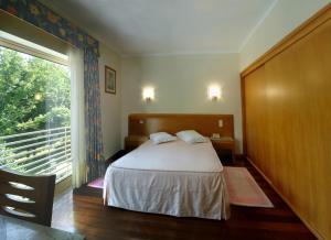 a bedroom with a bed and a large window at Hotel Caldelas in Caldelas