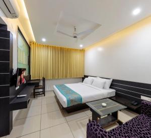 een hotelkamer met een bed en een televisie bij Hotel Radiant in Kolhapur