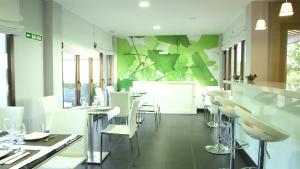 un restaurante con sillas blancas y una pared verde en Hotel Rural Noalla, en Noalla