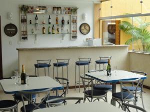 two tables and chairs in a restaurant with bottles at Village du Soleil in Cabo Frio