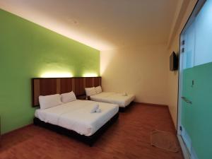 two beds in a room with green walls at Sweet Star Hotel in Alor Setar