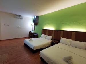 ein Hotelzimmer mit 2 Betten und einer grünen Wand in der Unterkunft Sweet Star Hotel in Alor Setar