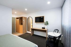 a bedroom with a bed and a desk and a tv at Aden Hotel Mudgee in Mudgee