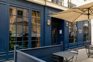 パリにあるMaison Barbèsの建物前のカフェ(テーブル、傘付)