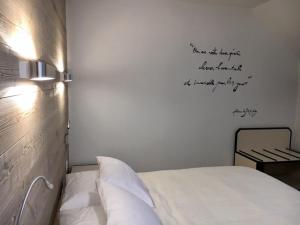 a bedroom with a bed with writing on the wall at Logis Hôtel "Ici m'aime" in Rouvray