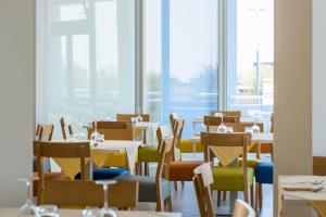 a dining room with tables and chairs and windows at Hotel Mediterraneo in Sottomarina