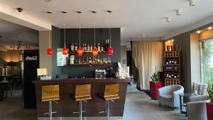 a restaurant with a bar with chairs and lights at Comm Hotel Poznań Airport in Poznań