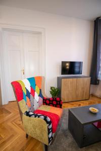 uma sala de estar com uma cadeira colorida e uma televisão em Frui Centro Zagreb em Zagreb