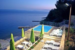 a pool with chairs and umbrellas next to the water at Apartments Nostro in Omiš