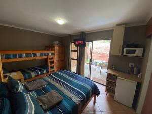 um quarto com uma cama e uma porta para um pátio em Mount Nebo Hillside Reserve em Muldersdrift