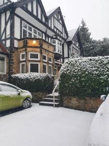 a house with a car parked in the snow at Cosy 2Bed Apartment near Roundhay Park in Moortown