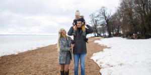 Ein Mann, der ein Kind auf seinen Schultern am Strand hält. in der Unterkunft Repinskaya Hotel in Repino