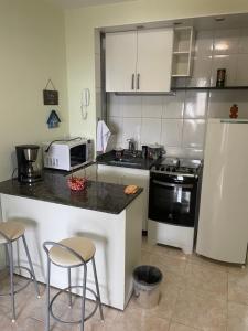 a kitchen with a counter with stools and a refrigerator at Copacabana Vista parcial do Mar, melhor ponto de Copacabana in Rio de Janeiro +10 photos