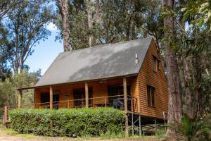 a log cabin in the woods with a metal roof at Noble River Estate in Dwellingup