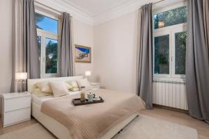 a white bedroom with a bed and two windows at Villa Sokol Apartments Opatija center in Opatija
