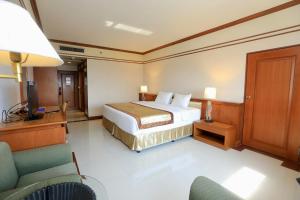 um quarto de hotel com uma cama e uma televisão e cadeiras em Kosa Hotel & Wellness Center -SHA Certified em Khon Kaen