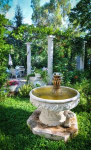 a large stone fountain in a garden with a bench at Apartments Villa Stankovic in Tivat