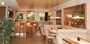un restaurante con mesas y sillas blancas y un bar en Waldhotel Bad Soden, en Bad Soden am Taunus