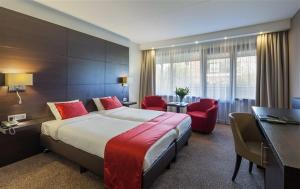 a hotel room with a large bed and red chairs at Van der Valk Hotel Avifauna in Alphen aan den Rijn