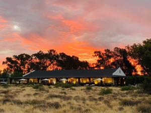 un edificio en medio de un campo con una puesta de sol en Sweetfontein Boutique Farm Lodge, en Britstown