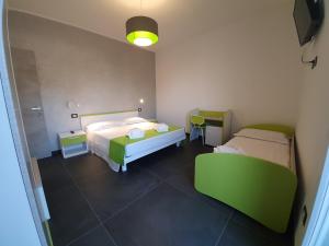Un dormitorio con dos camas y un sofá verde. en Evergreen B&B, en Porto Cesareo