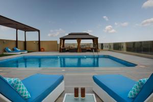 a swimming pool with chairs and a gazebo at ABAR HOTEL APARTMENTS DIP-1 in Dubai
