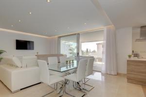 a dining room with a glass table and white chairs at New Modern 3 Bed Apartment Puerto Banus in Marbella