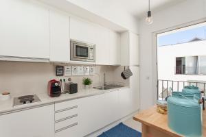 a white kitchen with a sink and a microwave at Lisbon Lifestyle House in Lisbon