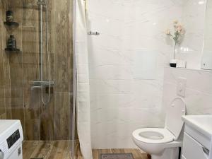 Un baño blanco con inodoro y ducha. en Lux apartment on Astana 12/1, en Öskemen 7 fotos más