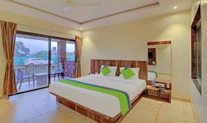a bedroom with a large bed and a balcony at Treebo Trend Nakshatra Cottages Mahabaleshwar in Mahabaleshwar