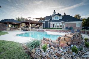 a house with a swimming pool with rocks in front of it at Luxury 5 Acre Private Estate on Lake Ray Roberts in Sanger