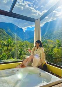a woman sitting in a bath tub with a glass of wine at Refúgio Ecológico Pedra Afiada in Praia Grande +250 photos
