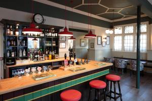 un bar en un restaurante con taburetes rojos en The Crabtree Inn en Shoreham-by-Sea