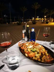 a plate of food on a table with glasses of wine at Hostal S'Algaret in Fornells