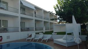 a hotel with chairs and umbrellas next to a pool at Hostal S'Algaret in Fornells