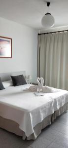 a bedroom with a white bed with a bow on it at Hostal S'Algaret in Fornells