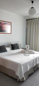 1 dormitorio con 1 cama grande con manta blanca en Hostal S'Algaret, en Fornells