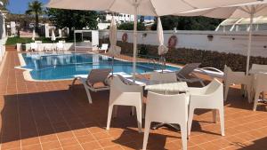 a table with chairs and an umbrella next to a pool at Hostal S'Algaret in Fornells