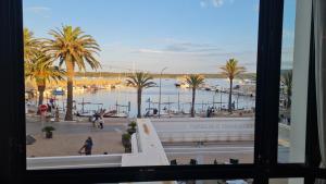 a view from a window of a marina with palm trees at Hostal S'Algaret in Fornells