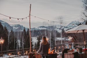 a woman standing on a balcony looking at the mountains at SEEBICHL haus am see Designhotel Kitzbühel in Kitzbühel