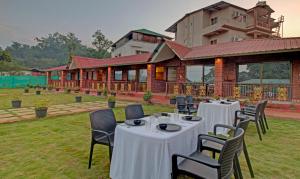 un grupo de mesas y sillas frente a un edificio en Treebo Trend Nakshatra Cottages Mahabaleshwar en Mahābaleshwar