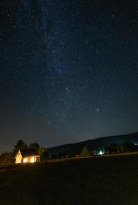 une maison sous un ciel étoilé la nuit dans l'établissement Pastelova Krova - domki w Bieszczadach, à Ustrzyki Dolne