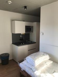 a room with a kitchen with a bed and a microwave at SITE.INN Hamburg in Hamburg