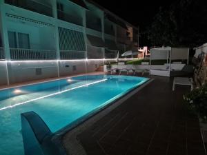 a swimming pool with chairs next to a building at night at Hostal S'Algaret in Fornells