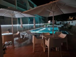 a patio with tables and umbrellas next to a pool at Hostal S'Algaret in Fornells