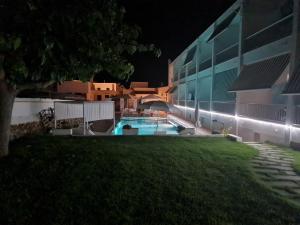 a building with a swimming pool at night at Hostal S'Algaret in Fornells