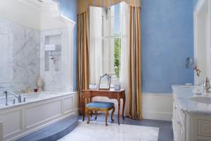 baño con bañera, lavabo y ventana en The Lanesborough, Oetker Collection en Londres