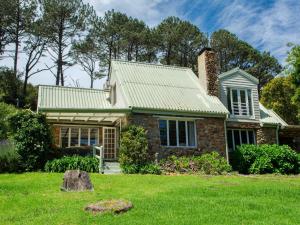 a brick house with a metal roof on a yard at Houtkapperspoort Mountain Cottages in Cape Town